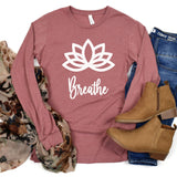 Heather Mauve Long Sleeve shirt in center with white Lotus flower and word Breathe underneath on shirt.  Shirt surrounded by a scarf to the left and blue jeans with brown ankle boots to the right.