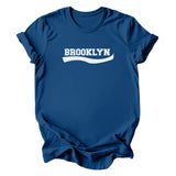 A royal blue short-sleeve t-shirt with 'BROOKLYN' printed in white across the chest, styled with a wavy underline graphic, shown on a plain white background.