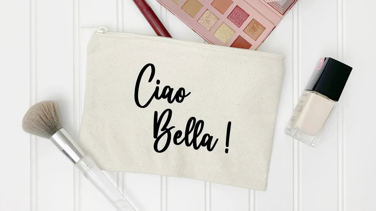Beige pouch with 'Ciao Bella!' text, makeup brush, and nail polish on a white background