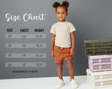Child standing next to a size chart with measurements on a gray background
