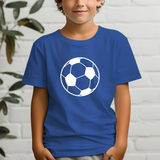 A child wearing a royal blue short-sleeve t-shirt with a white soccer ball graphic on the chest, standing against a white brick wall with a plant in the background.